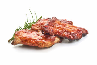 Delicious grilled pork ribs in BBQ sauce with herbs, isolated on white background